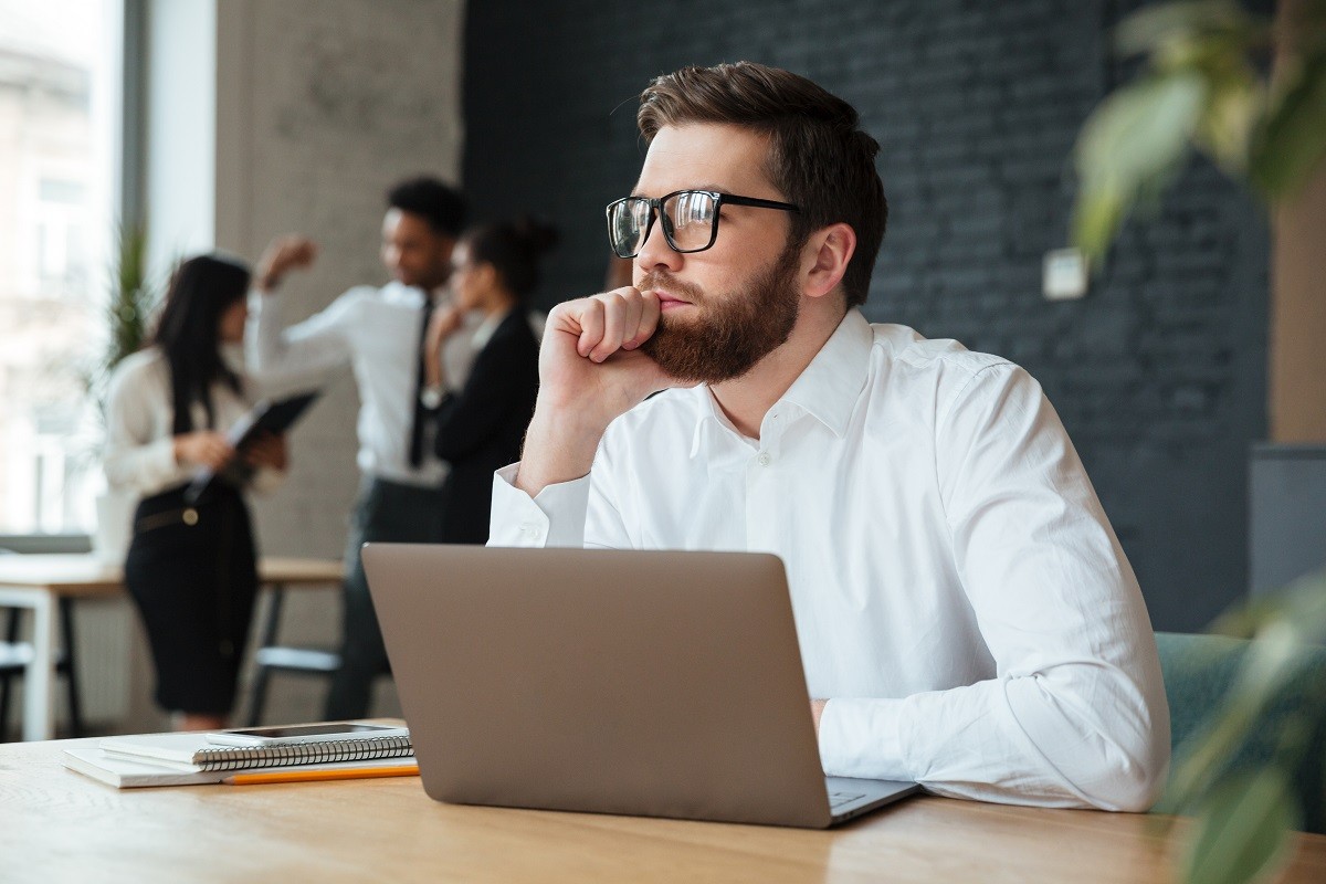 A man is deep in thought with people in the background